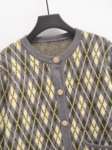 Detail of argyle knit cardigan with ribbed crew neck and ornate bronze buttons