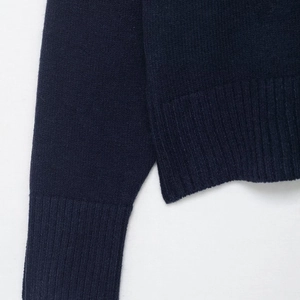 Close-up of dark blue knit sweater showing ribbed cuffs and hem with fine stitching
