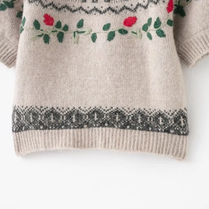 Detailed embroidery and jacquard patterns on beige knit sweater hem with ribbed edges
