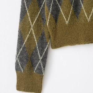 Detailed view of argyle knit pattern and ribbed cuffs on the olive green polo sweater