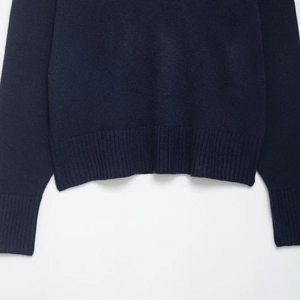 Detail view of the fine ribbed hem and sleeve cuffs on this navy blue V-neck knit sweater