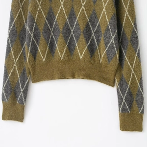 Detail of cropped argyle knit sweater showing olive green and grey diamond pattern texture