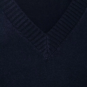 Close-up of ribbed V-neckline detail on a soft navy blue knitted sweater with fine texture