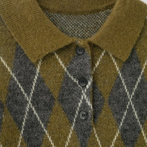 Detailed view of argyle knit polo sweater with olive green pattern and wool texture