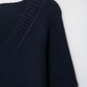 Detailed close-up of the ribbed V-neckline on a soft navy blue knitted sweater