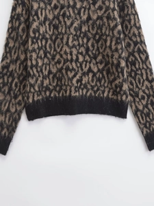 Detailed macro shot of leopard print knit fabric with black ribbed cuffs and fuzzy texture