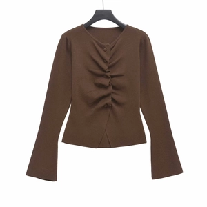 Detail view of dark brown knitted sweater featuring vertical ruching and round neck