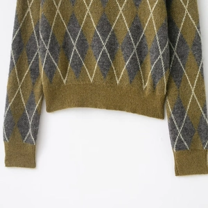 Close-up of argyle knit pattern and ribbed hem on this olive green polo sweater