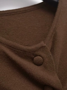Close-up of dark brown knit cardigan showing soft wool fabric texture and matching button detail