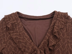 Detailed macro view of the ruffled V-neckline and hollow knit mesh texture on brown dress