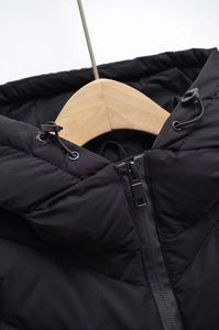 Detailed close-up of zipper and adjustable drawstring hood on black winter jacket