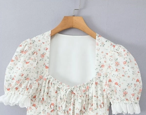 Detail of square neck floral mini dress with lace-trimmed puff sleeves and tie-up front