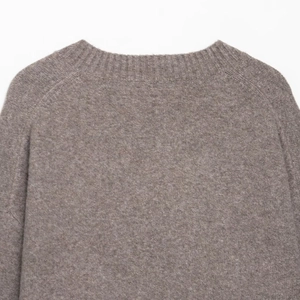 Close-up of ribbed knit neckline and raglan sleeve texture on brown V-neck sweater