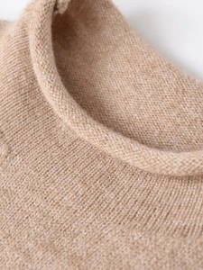 Detailed macro view of khaki knit sweater showing rolled crew neck and fine ribbed texture