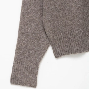 Close-up of soft ribbed cuffs and high-quality knit texture on a tan V-neck sweater