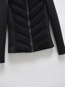 Close-up of black padded jacket showing V-quilted texture and sleek zip details