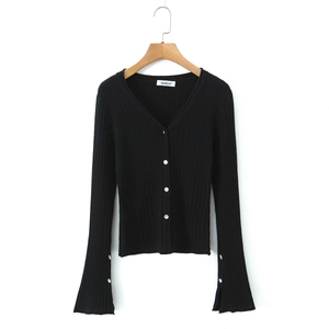 Détail d'un cardigan noir en maille à col en V avec manches trompette et boutons blancs