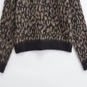 Women's crew neck knitted sweater featuring bold leopard print and black ribbed cuffs