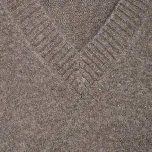 Detail shot of V-neck ribbed neckline on soft brown knit sweater with premium wool texture