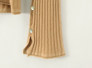 Détail macro du tricot côtelé beige avec fente latérale et boutons nacrés élégants