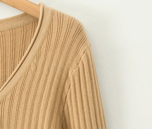 Gros plan du cardigan en maille kaki à col en V montrant la texture côtelée et le tissu doux