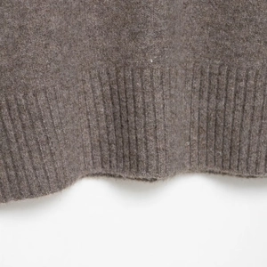 Close-up of soft brown knit sweater texture featuring premium ribbed edge details