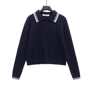 Detail of navy knit polo sweater featuring white stripes on the collar and button placket