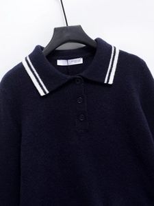 Detail of navy knit polo sweater featuring a striped collar and branded size label