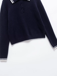 Detail of navy knit polo sweater featuring white stripes on collar and three buttons