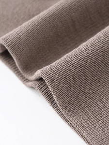 Macro detail of high-quality brown knit fabric showing soft texture and fine stitching