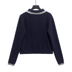 Detail view of the navy blue knit sweater featuring ribbed cuffs with white stripe accents