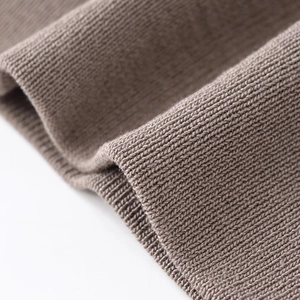 Detailed macro view of tan high-density knit fabric with fine vertical ribbing texture