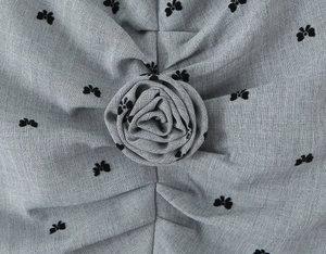 Close-up of a grey dress featuring a 3D rose flower detail and black flocked floral patterns