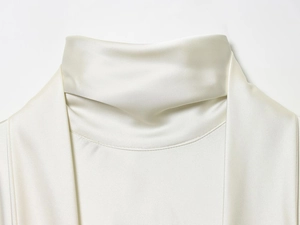 Detail shot of white satin high collar dress showing smooth fabric texture and folds