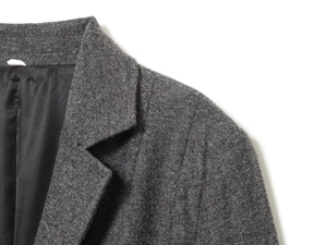 Détail d'un blazer en tweed gris foncé montrant le revers et la doublure en soie