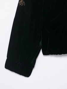 Detail der schwarzen Samtjacke mit goldener Blumenstickerei und elastischen Rippbündchen