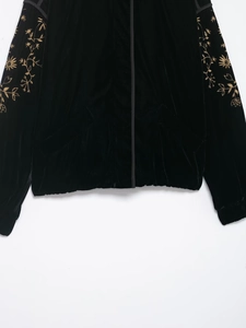 Detailansicht der schwarzen Samtjacke mit aufwendiger goldener Blumenstickerei am Ärmel