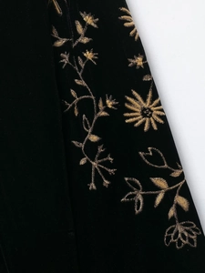 Detailaufnahme der aufwendigen goldenen Blumenstickerei auf schwarzem Samtstoff