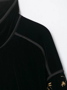 Detail der schwarzen Samtjacke mit Stehkragen und goldener Sternenstickerei am Ärmel