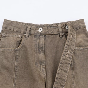 Detailed close-up of distressed denim waist with asymmetric double-button closure