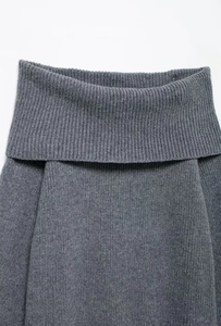 Detail der grauen Rippstrick-Struktur und des eleganten Off-Shoulder-Kragens am Pullover
