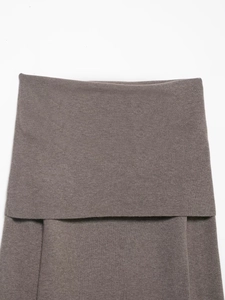 Macro detail of dark brown knit fabric showing the textured weave and off-the-shoulder fold