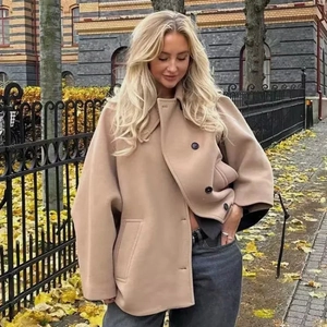 Détail d'une veste en laine camel à boutonnage simple et col tailleur sur fond urbain automnal