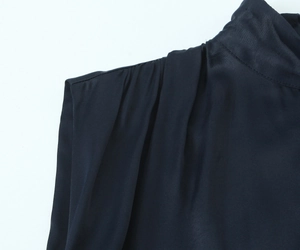 Detailed view of sophisticated pleated shoulders and stand-up collar on a satin dress