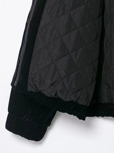 Details einer schwarzen Samtjacke mit gestepptem Rautenmuster und Rippbündchen