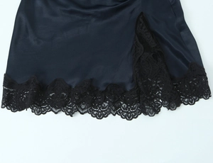 Detail of dark blue satin dress hem featuring exquisite black lace trim and side slit