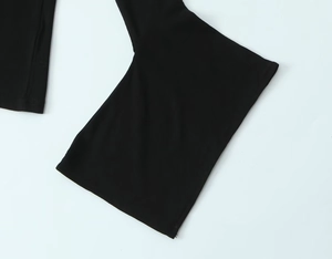 Close-up of black ribbed knit fabric showing the flared hem and texture of the pants