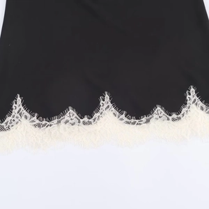 Detail of delicate white eyelash lace trim on a contrasting black satin camisole top