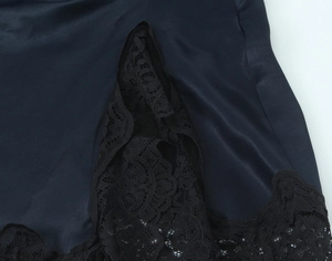 Close-up of black satin dress hem with intricate floral lace trim and smooth texture