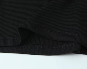 Detail of black ribbed knit fabric showing fine vertical texture and neat double stitching